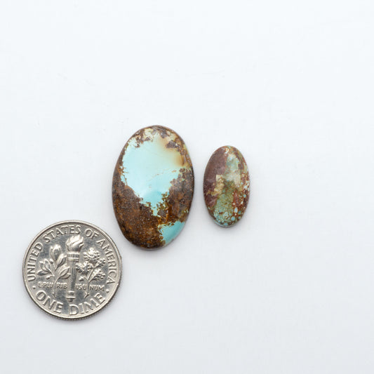 Golden Hills Turquoise cabochons, icy blue to lavender tones with chocolate matrix, polished stones on a white background with a US dime for scale