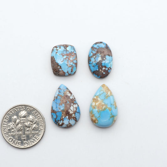 Golden Hills Turquoise cabochons, icy blue to lavender tones with chocolate matrix, polished stones on a white background with a US dime for scale
