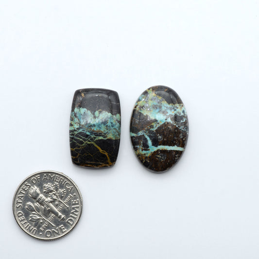 Black Jack turquoise cabochons, blue-green color with black matrix, polished stones on a white background with a US dime for scale