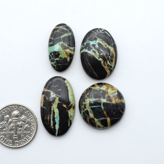 Black Jack turquoise cabochons, blue-green color with black matrix, polished stones on a white background with a US dime for scale