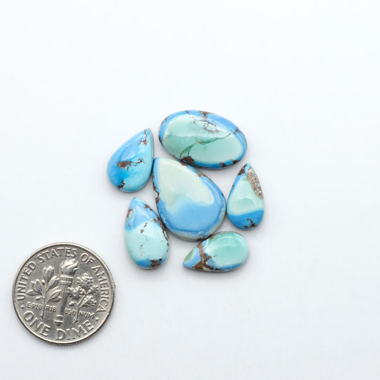 Golden Hills Turquoise cabochons, icy blue to lavender tones with chocolate matrix, polished stones on a white background with a US dime for scale