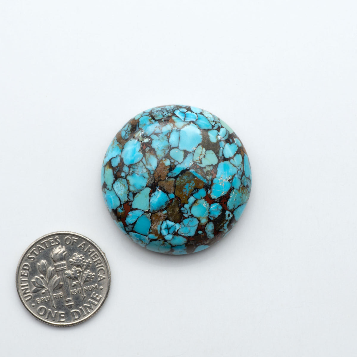Pressed Turquoise nugget cabochons, composite material with a blue color and dark matrix on a white background, with a US dime for scale.