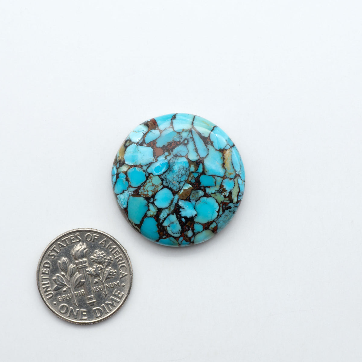 Pressed Turquoise nugget cabochons, composite material with a blue color and dark matrix on a white background, with a US dime for scale.