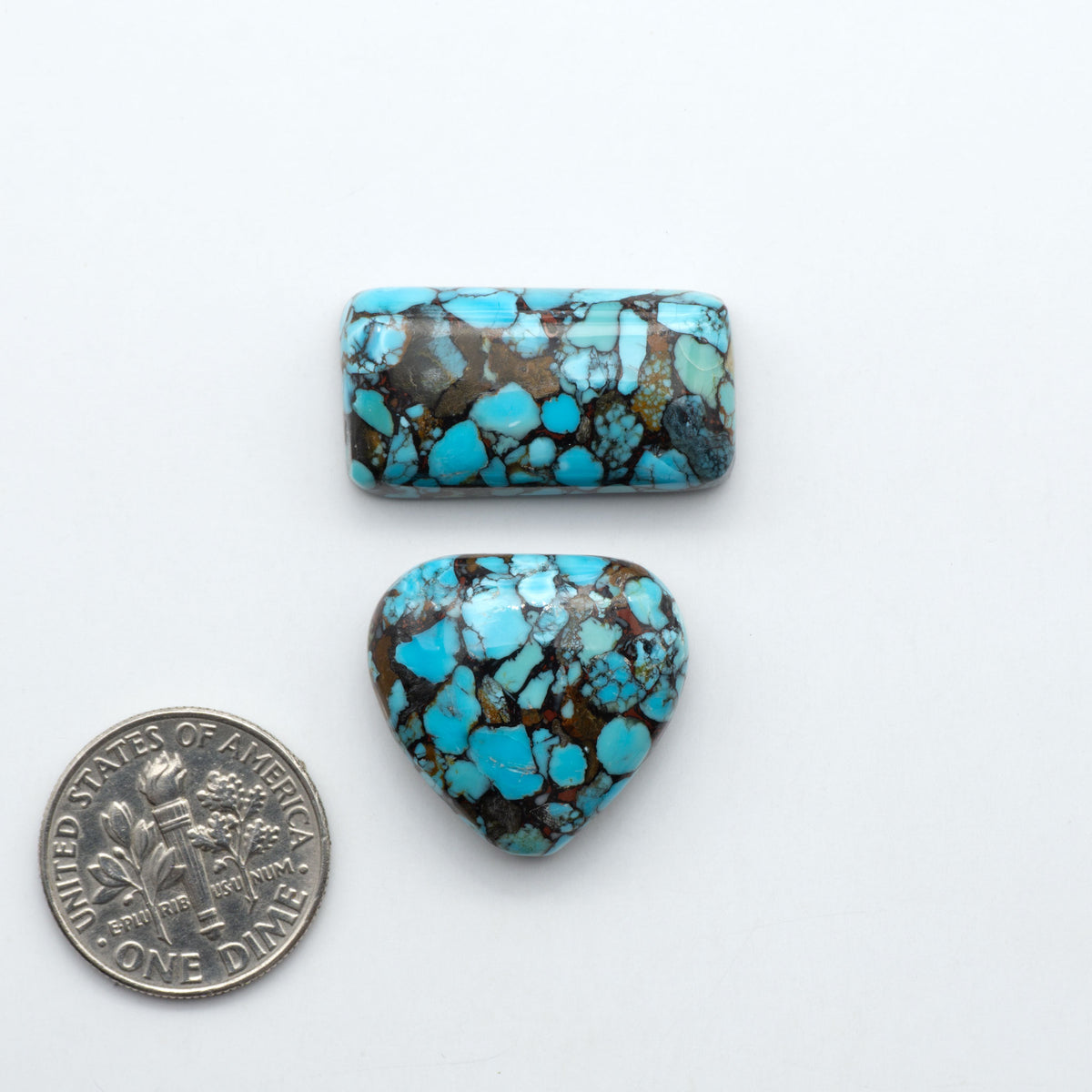 Pressed Turquoise nugget cabochons, composite material with a blue color and dark matrix on a white background, with a US dime for scale.