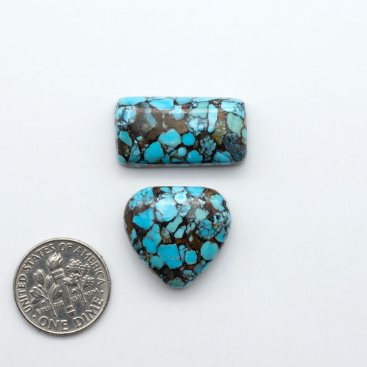 Pressed Turquoise nugget cabochons, composite material with a blue color and dark matrix on a white background, with a US dime for scale.