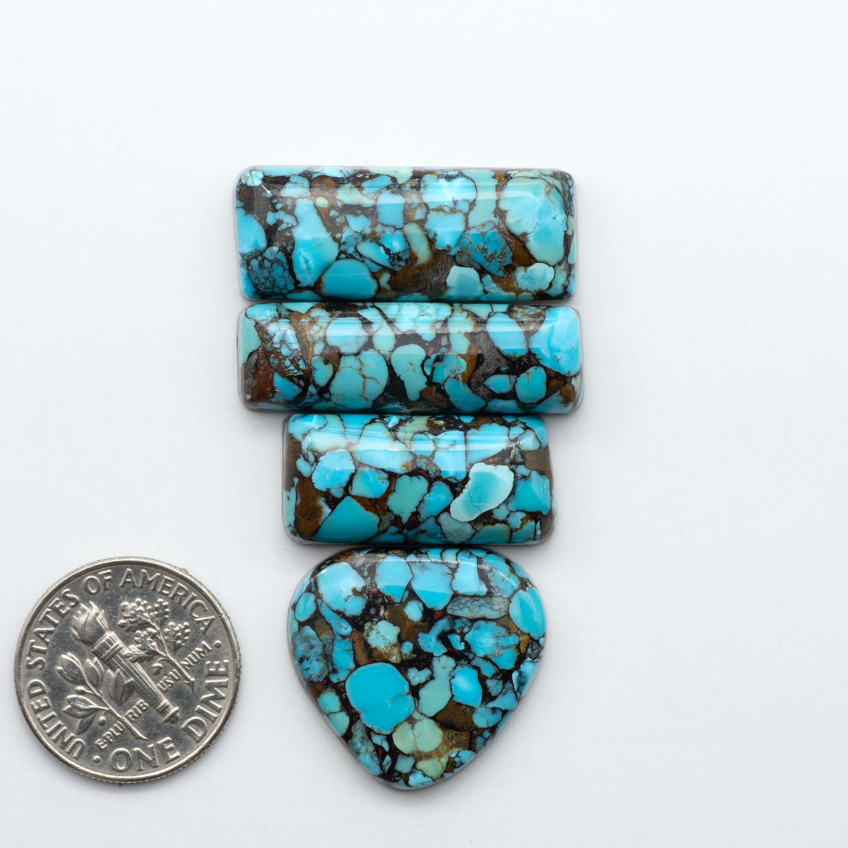 Pressed Turquoise nugget cabochons, composite material with a blue color and dark matrix on a white background, with a US dime for scale.