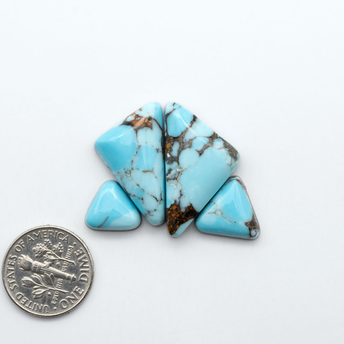 Pressed Turquoise nugget cabochons, composite material with a blue color and dark matrix on a white background, with a US dime for scale.