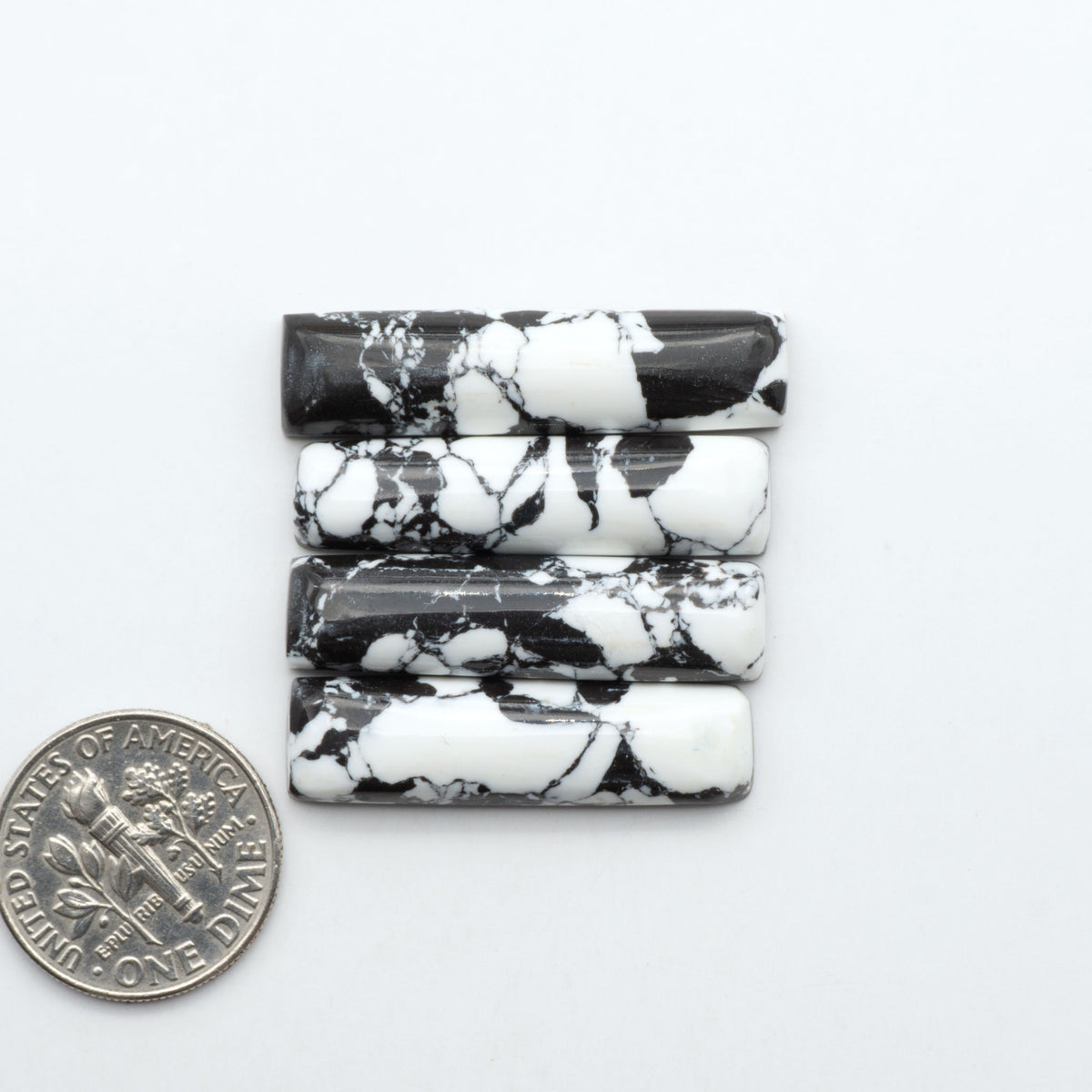 White Buffalo composite cabochons, black and white gemstones on a white background with a US dime for scale