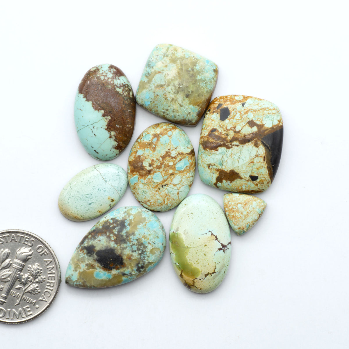 Number 8 Turquoise cabochons, blue and green color with brown matrix, polished stones on a white background, with a US dime for scale
