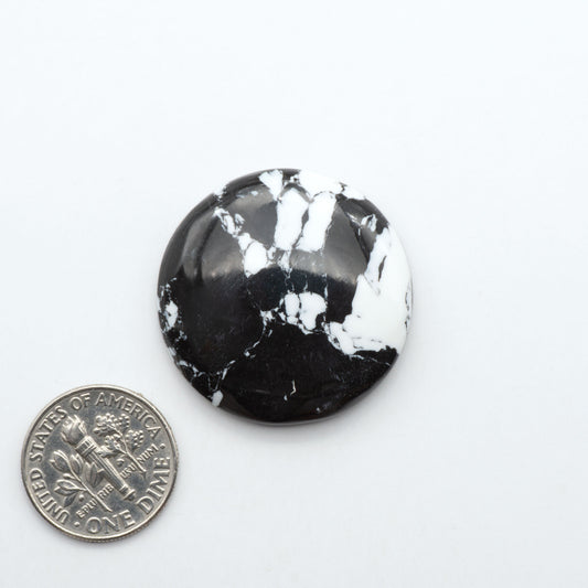 White Buffalo composite cabochons, black and white gemstones on a white background with a US dime for scale