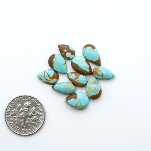 Number 8 Turquoise cabochons, blue and green color with brown matrix, polished stones on a white background, with a US dime for scale