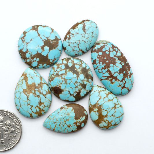 Number 8 Turquoise cabochons, blue and green color with brown matrix, polished stones on a white background, with a US dime for scale