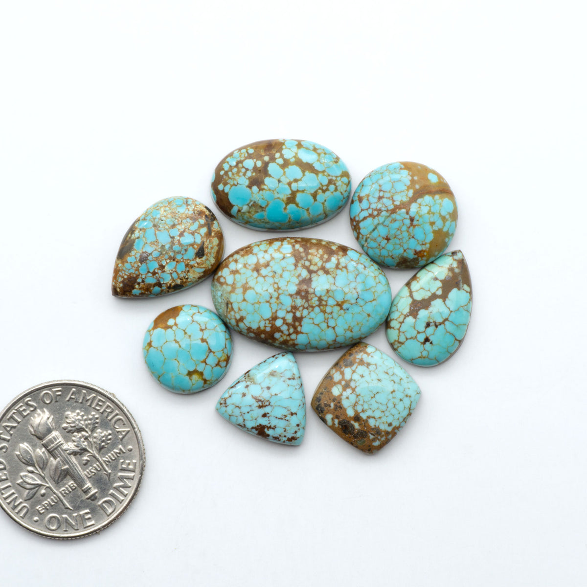 Number 8 Turquoise cabochons, blue and green color with brown matrix, polished stones on a white background, with a US dime for scale