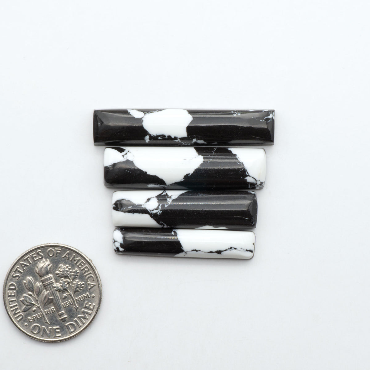 White Buffalo composite cabochons, black and white gemstones on a white background with a US dime for scale