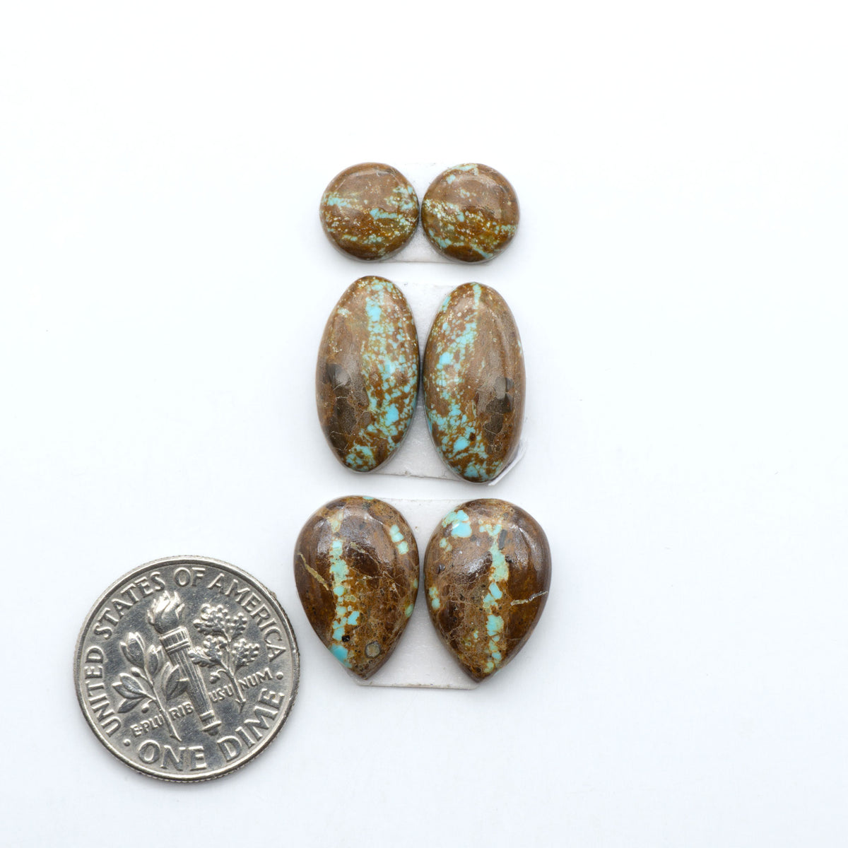 Number 8 Turquoise cabochons, blue and green color with brown matrix, polished stones on a white background, with a US dime for scale