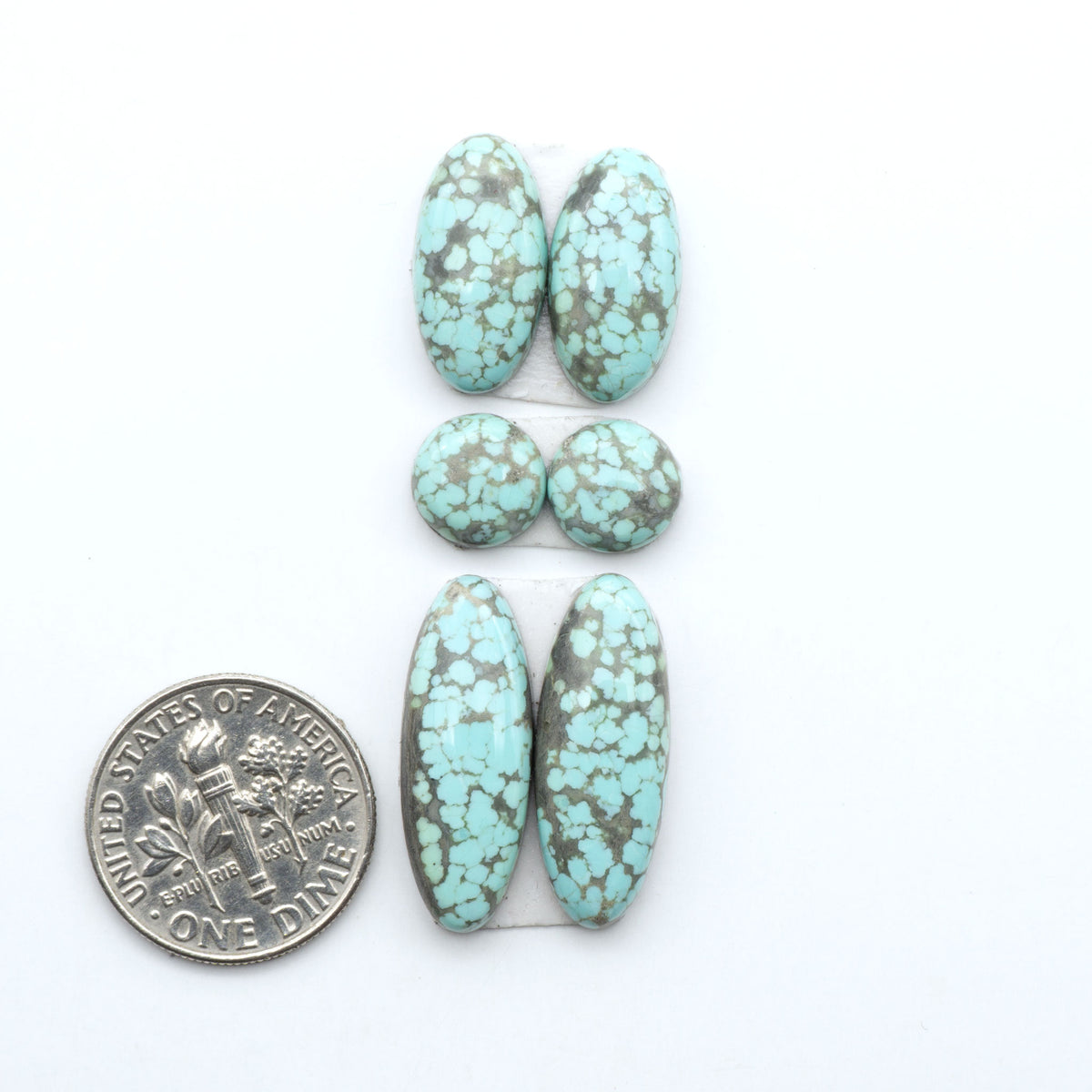 Number 8 Turquoise cabochons, blue and green color with brown matrix, polished stones on a white background, with a US dime for scale