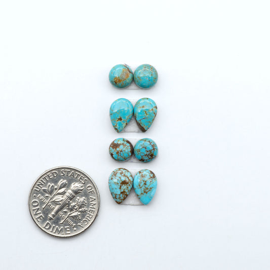 Number 8 Turquoise cabochons, blue and green color with brown matrix, polished stones on a white background, with a US dime for scale
