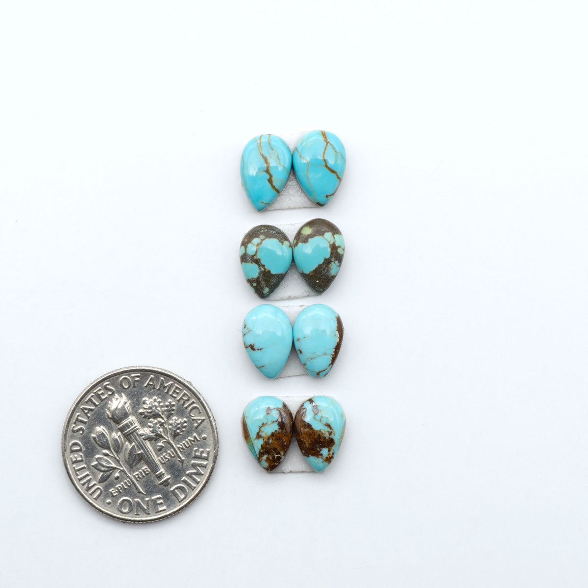 Number 8 Turquoise cabochons, blue and green color with brown matrix, polished stones on a white background, with a US dime for scale