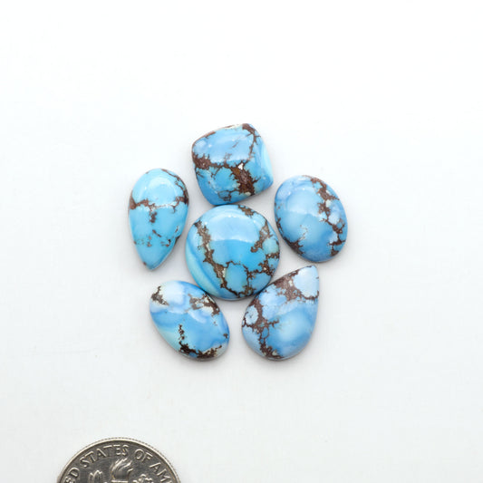 Golden Hills Turquoise cabochons, icy blue to lavender tones with chocolate matrix, polished stones on a white background with a US dime for scale
