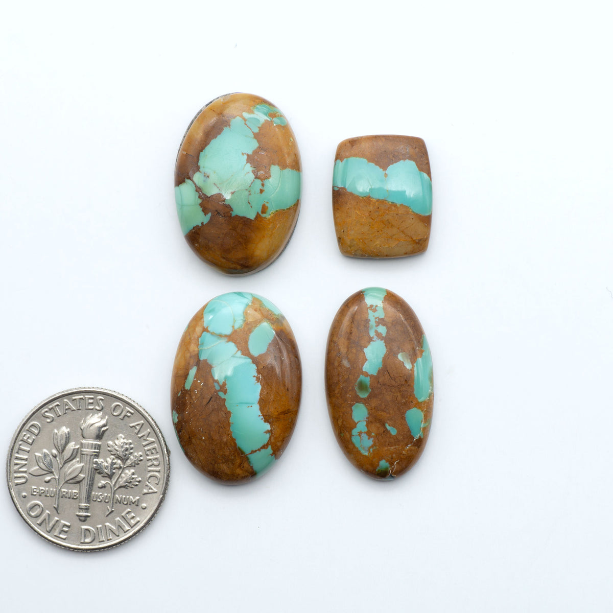 Pilot Mountain Turquoise cabochons, blue-green gemstones with natural matrix on a white background with a US dime for scale