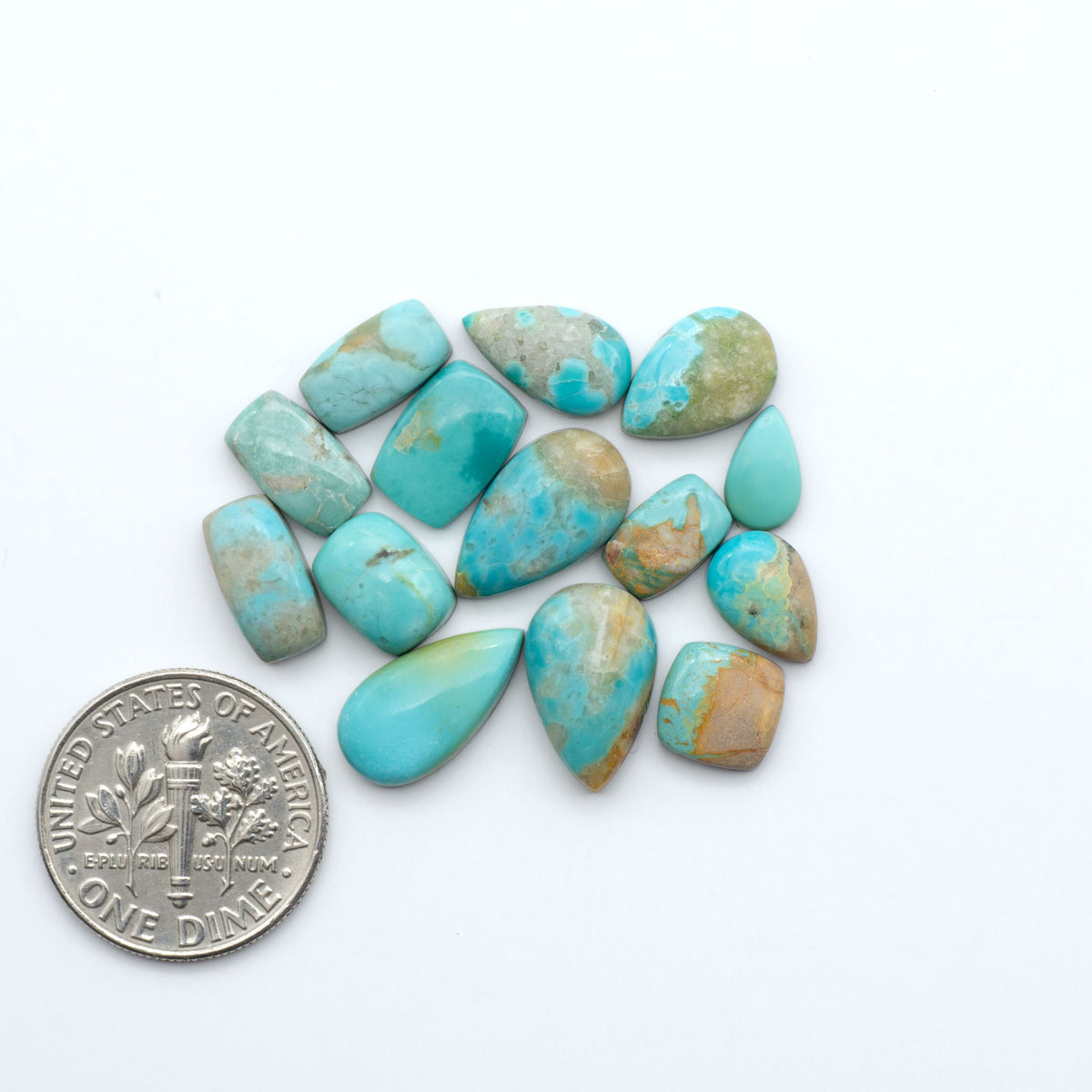 Kings Manassa Turquoise cabochons, polished green-blue gemstones with natural matrix on a white background with a US dime for scale