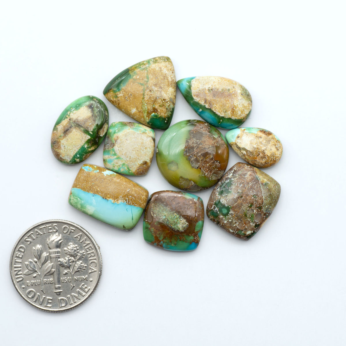 Sonoran Mountain Turquoise cabochons, blue-green color with natural matrix, polished stones on a white background, with a US dime for scale