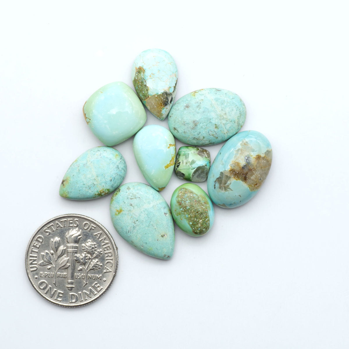 Sonoran Mountain Turquoise cabochons, blue-green color with natural matrix, polished stones on a white background, with a US dime for scale