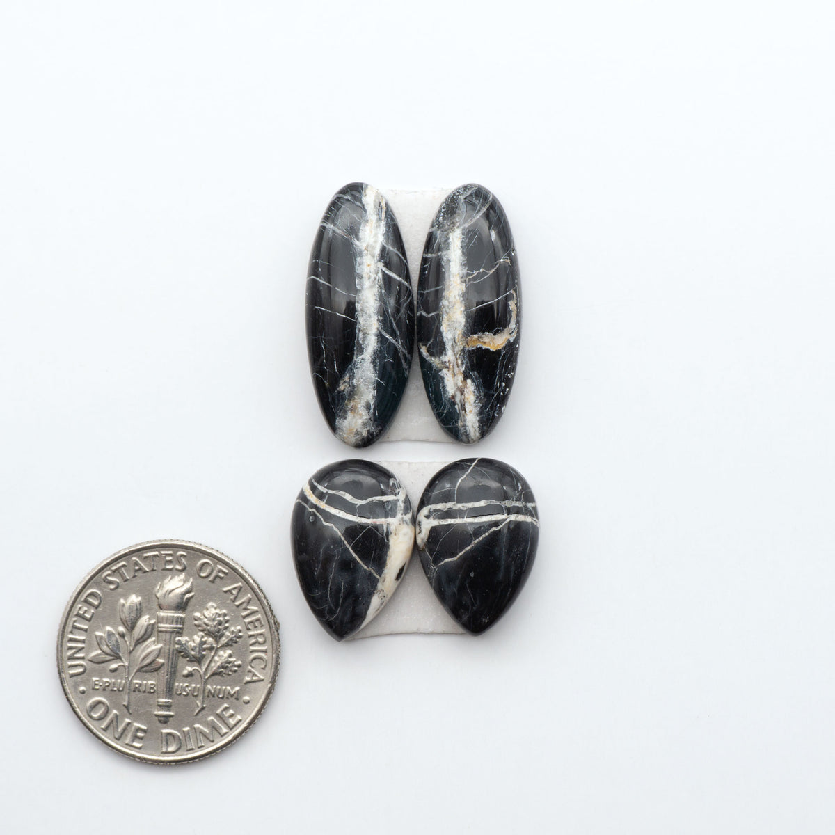 White Buffalo stone cabochons, white stone with black matrix, polished stones on a white background, with a US dime for scale