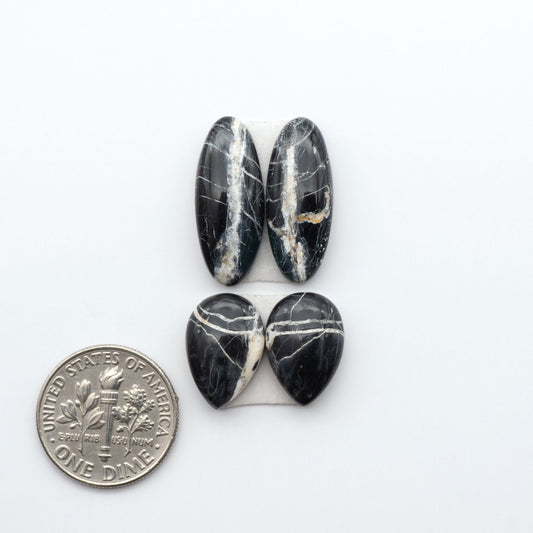 White Buffalo stone cabochons, white stone with black matrix, polished stones on a white background, with a US dime for scale