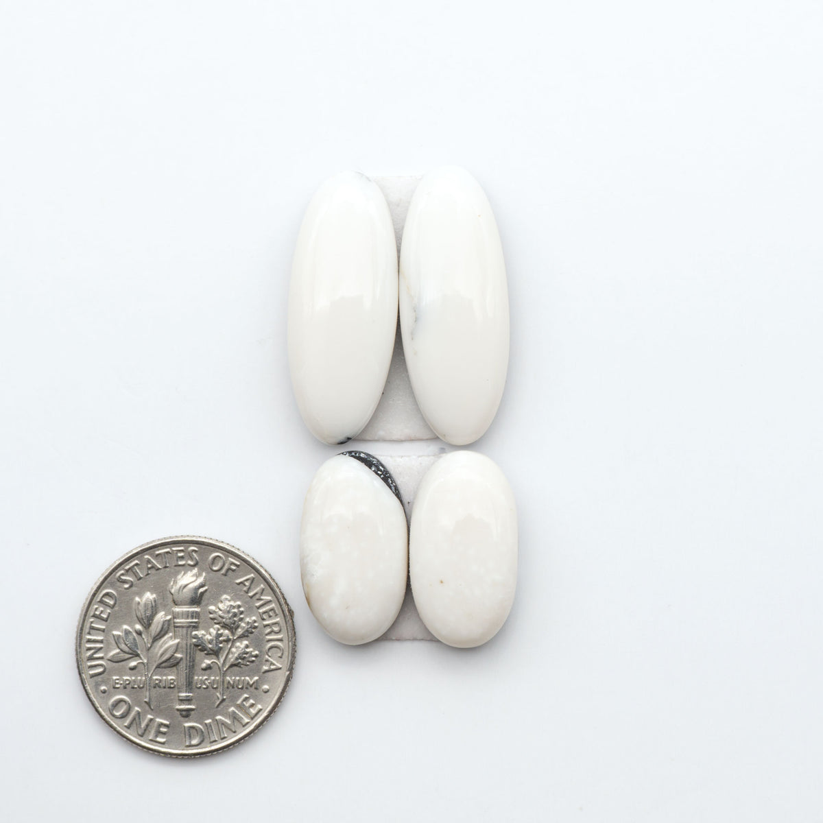 White Buffalo stone cabochons, white stone with black matrix, polished stones on a white background, with a US dime for scale