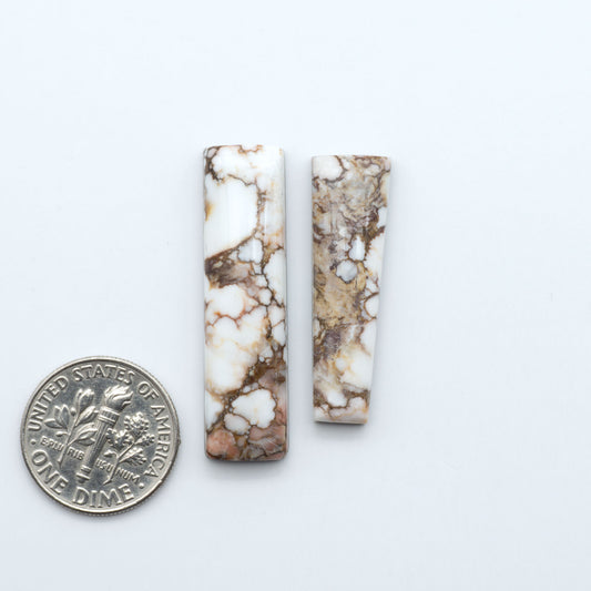Wild Horse Magnesite cabochons, white gemstones with brown matrix on a white background, with a US dime for scale