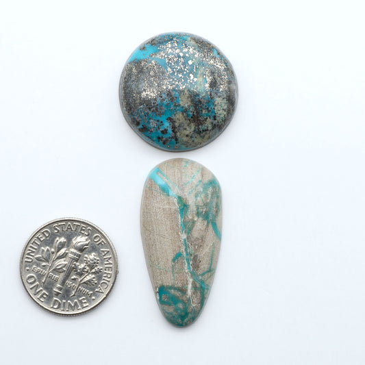 Assorted turquoise cabochon gemstones with varied colors and matrix on a white background with a US dime for scale