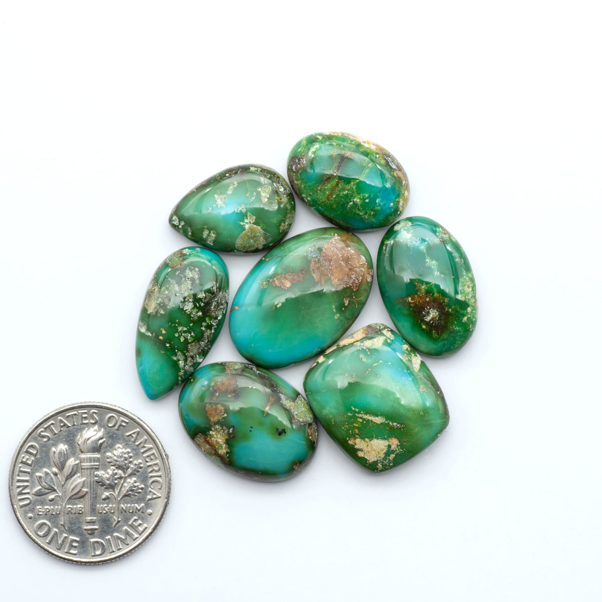 Sonoran Mountain Turquoise cabochons, blue-green color with natural matrix, polished stones on a white background, with a US dime for scale
