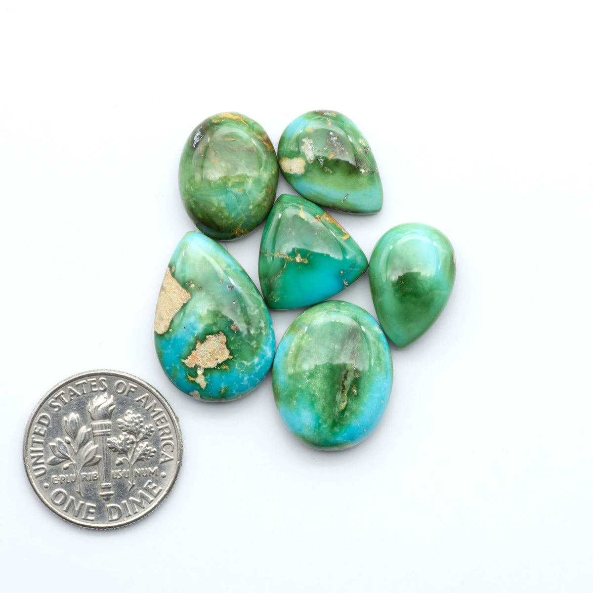 Sonoran Mountain Turquoise cabochons, blue-green color with natural matrix, polished stones on a white background, with a US dime for scale