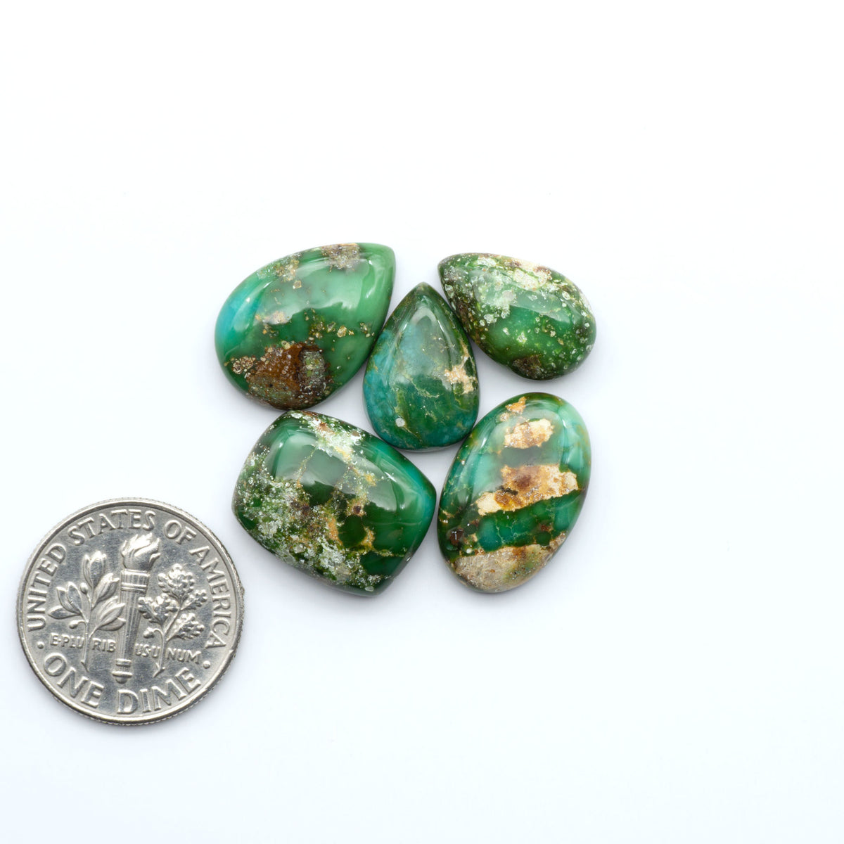 Sonoran Mountain Turquoise cabochons, blue-green color with natural matrix, polished stones on a white background, with a US dime for scale
