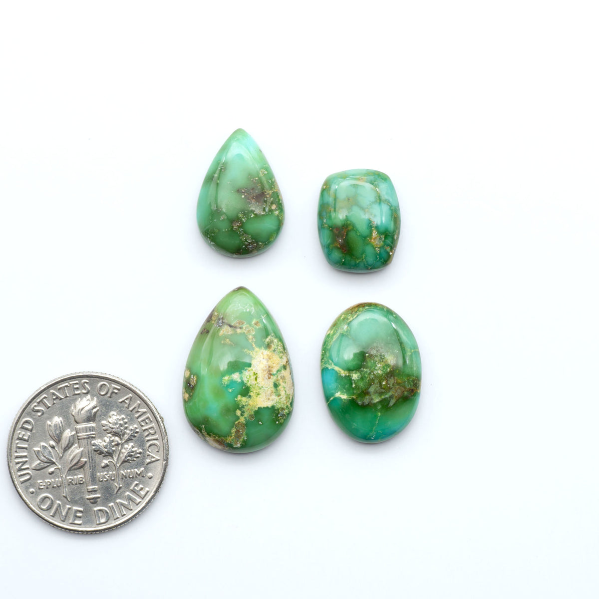 Sonoran Mountain Turquoise cabochons, blue-green color with natural matrix, polished stones on a white background, with a US dime for scale