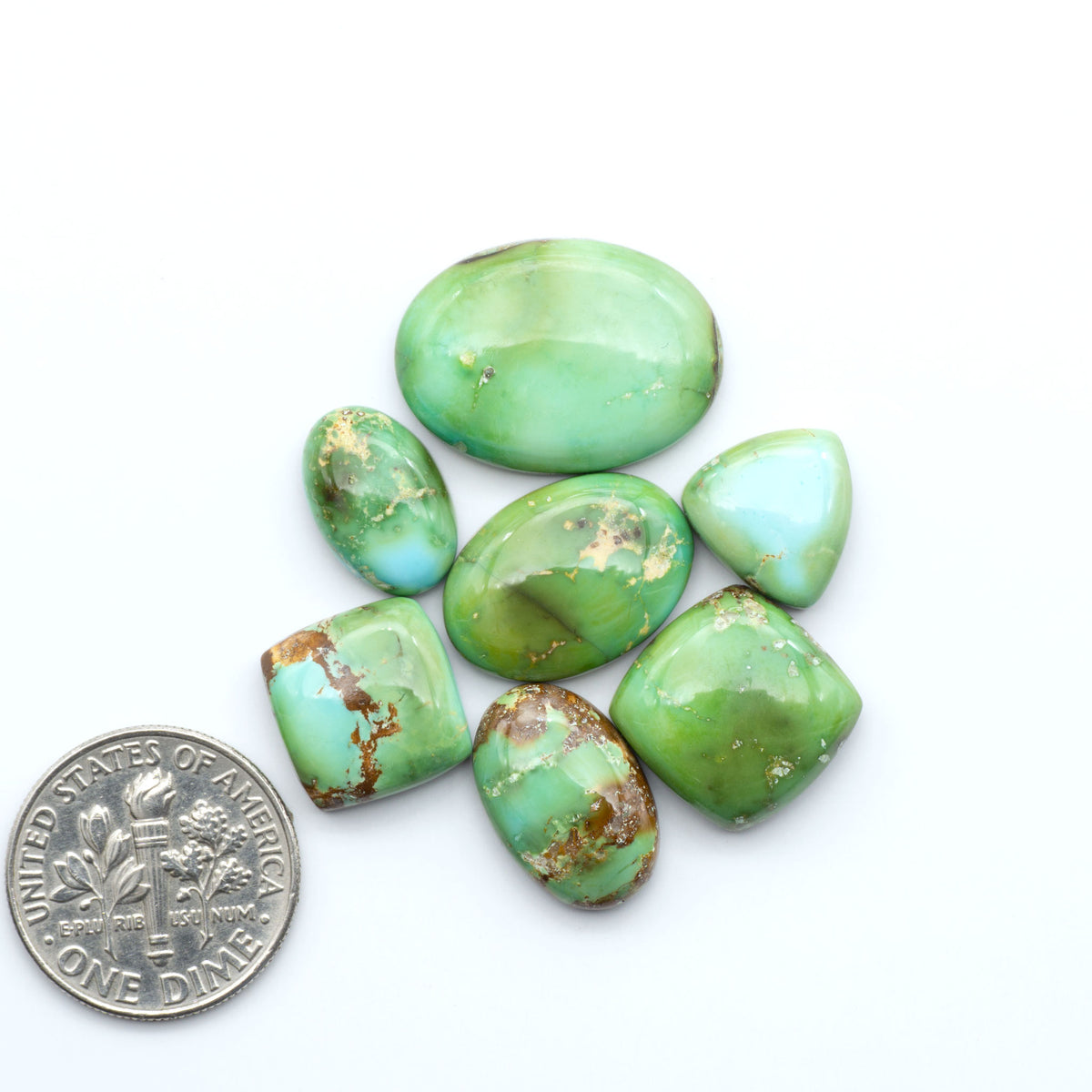 Sonoran Mountain Turquoise cabochons, blue-green color with natural matrix, polished stones on a white background, with a US dime for scale