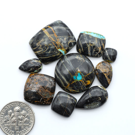 Black Jack turquoise cabochons, blue-green color with black matrix, polished stones on a white background with a US dime for scale