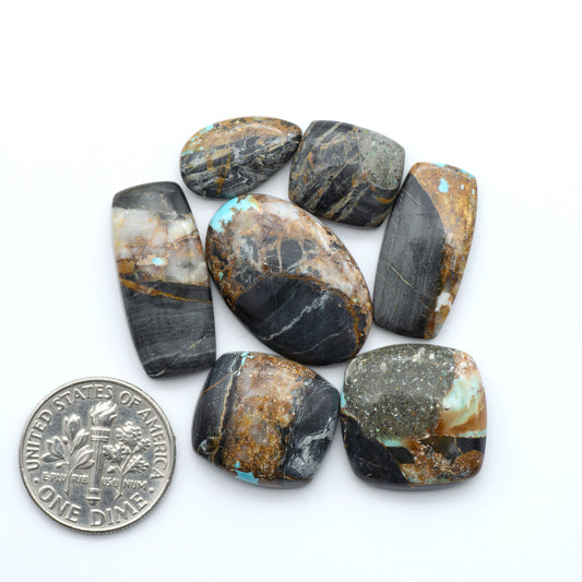 Black Jack turquoise cabochons, blue-green color with black matrix, polished stones on a white background with a US dime for scale