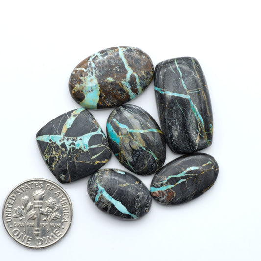 Black Jack turquoise cabochons, blue-green color with black matrix, polished stones on a white background with a US dime for scale