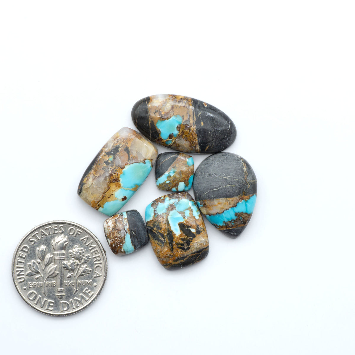 Black Jack turquoise cabochons, blue-green color with black matrix, polished stones on a white background with a US dime for scale