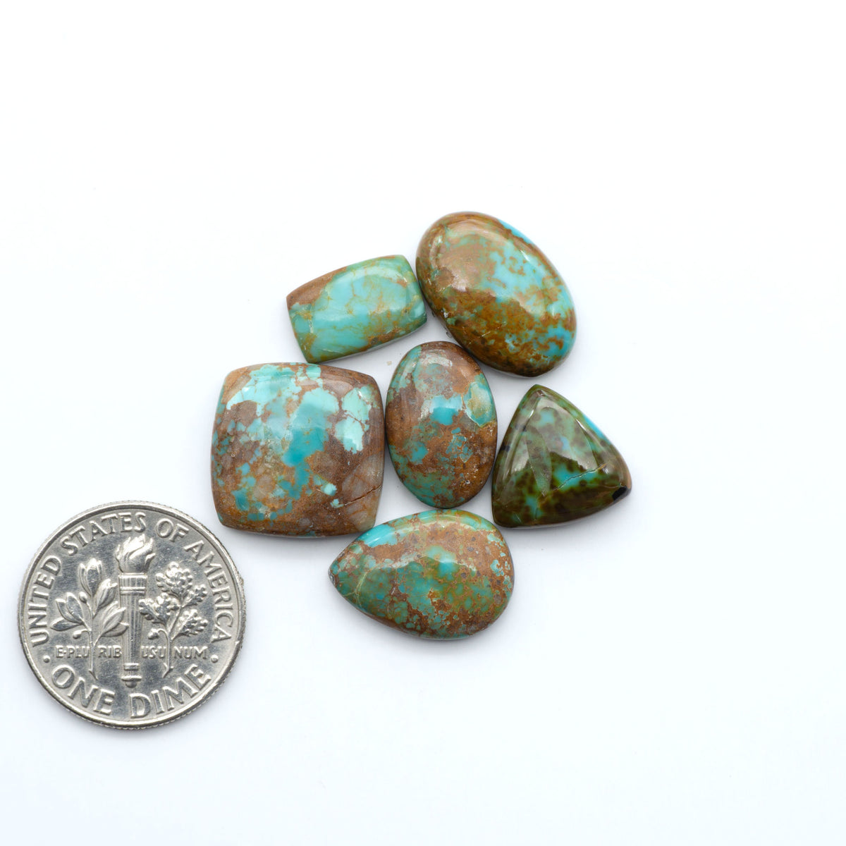 Pilot Mountain Turquoise cabochons, blue-green gemstones with natural matrix on a white background with a US dime for scale