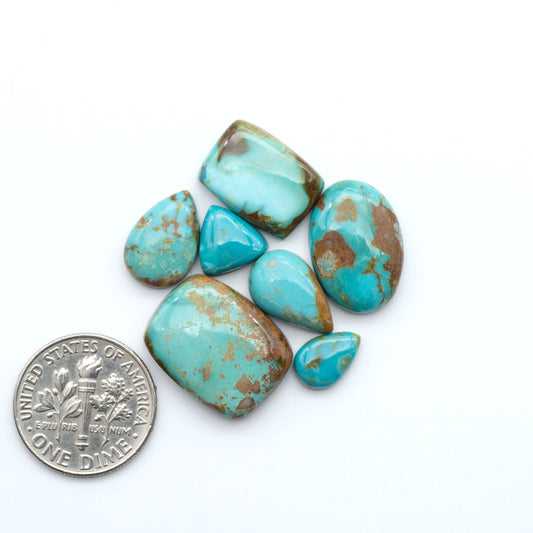 Pilot Mountain Turquoise cabochons, blue-green gemstones with natural matrix on a white background with a US dime for scale