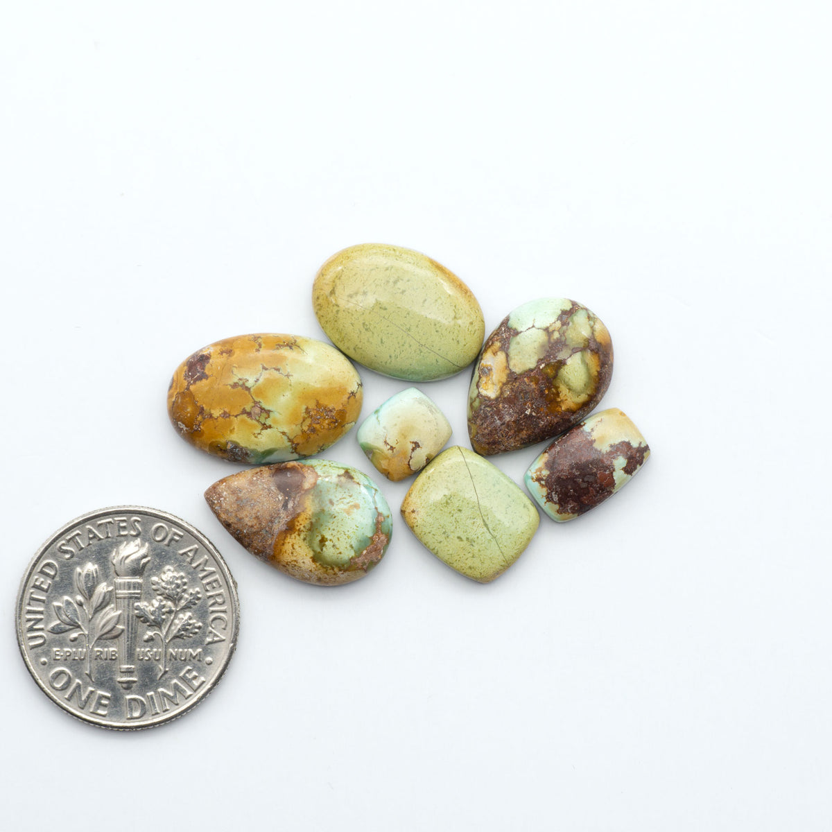 Golden Hills Turquoise cabochons, icy blue to lavender tones with chocolate matrix, polished stones on a white background with a US dime for scale