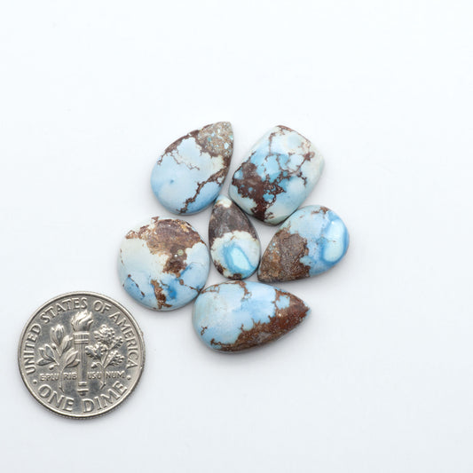 Golden Hills Turquoise cabochons, icy blue to lavender tones with chocolate matrix, polished stones on a white background with a US dime for scale