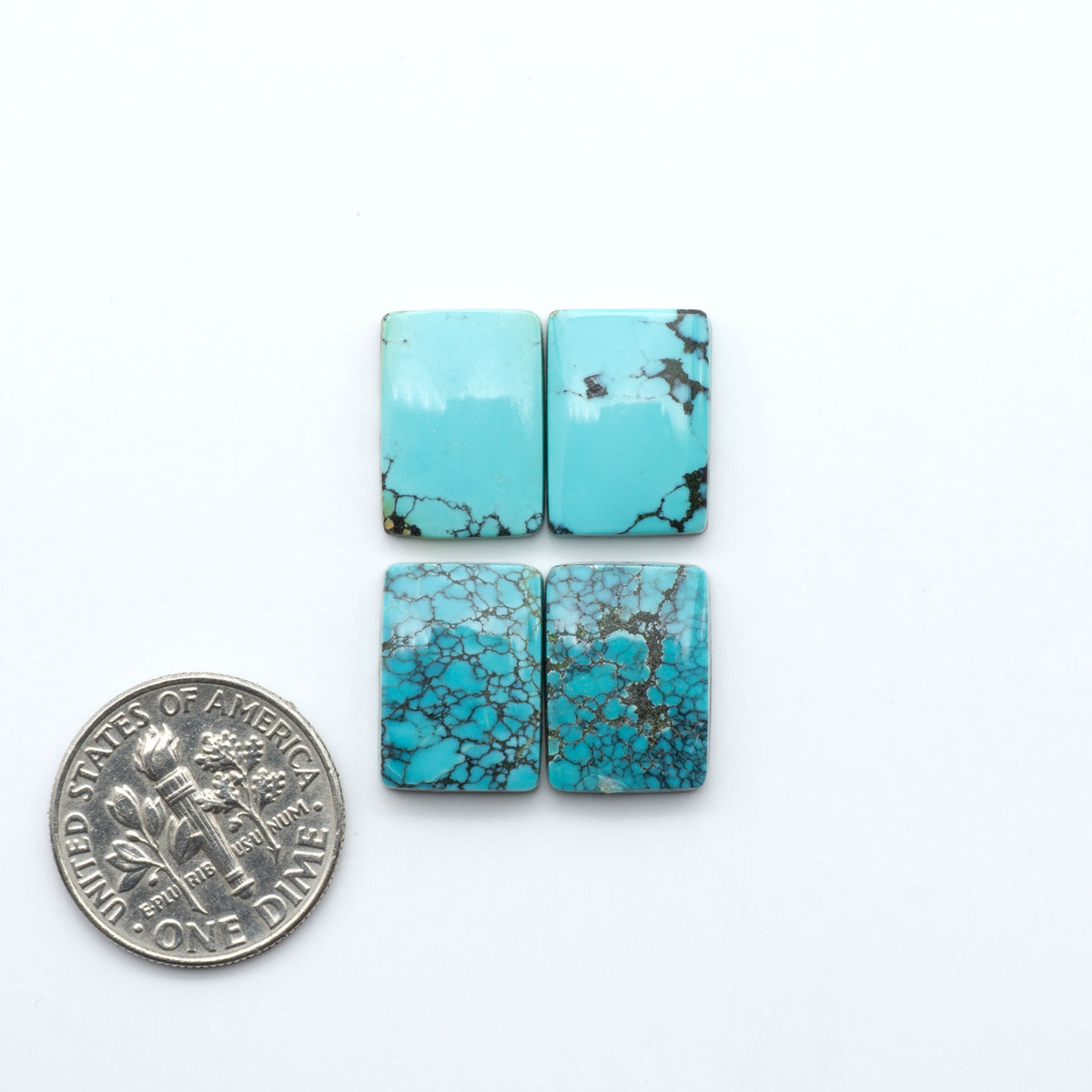 Hubei Cloud Mountain Turquoise cabochons, blue and green color with black matrix, polished stones on a white background, with a US dime for scale