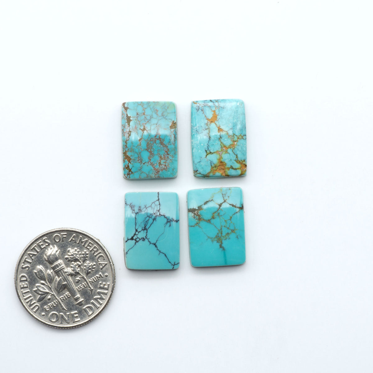 Hubei Cloud Mountain Turquoise cabochons, blue and green color with black matrix, polished stones on a white background, with a US dime for scale