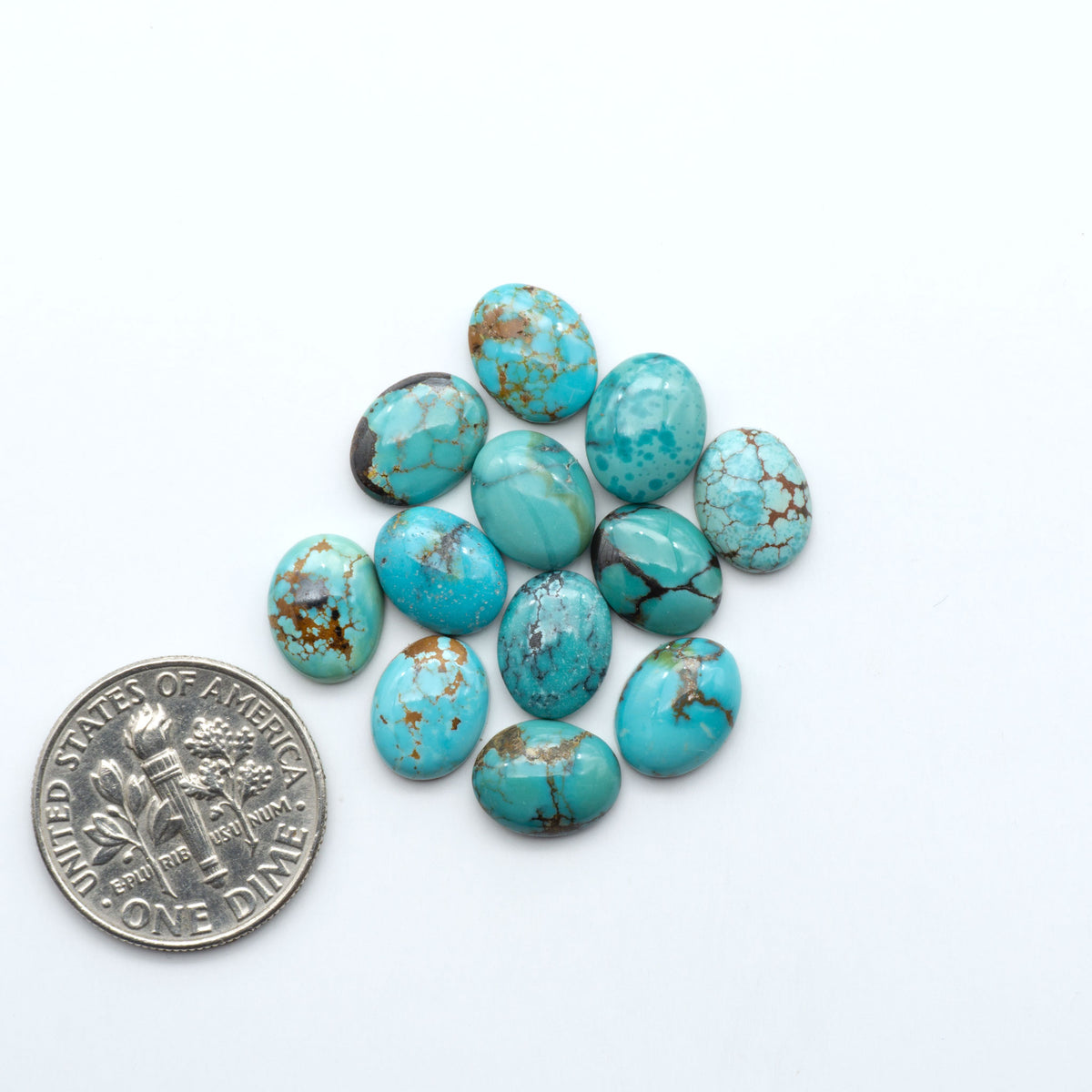 Hubei Cloud Mountain Turquoise cabochons, blue and green color with black matrix, polished stones on a white background, with a US dime for scale