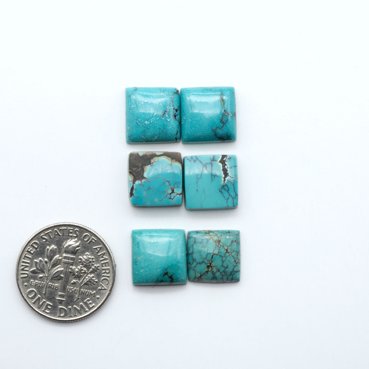 Hubei Cloud Mountain Turquoise cabochons, blue and green color with black matrix, polished stones on a white background, with a US dime for scale