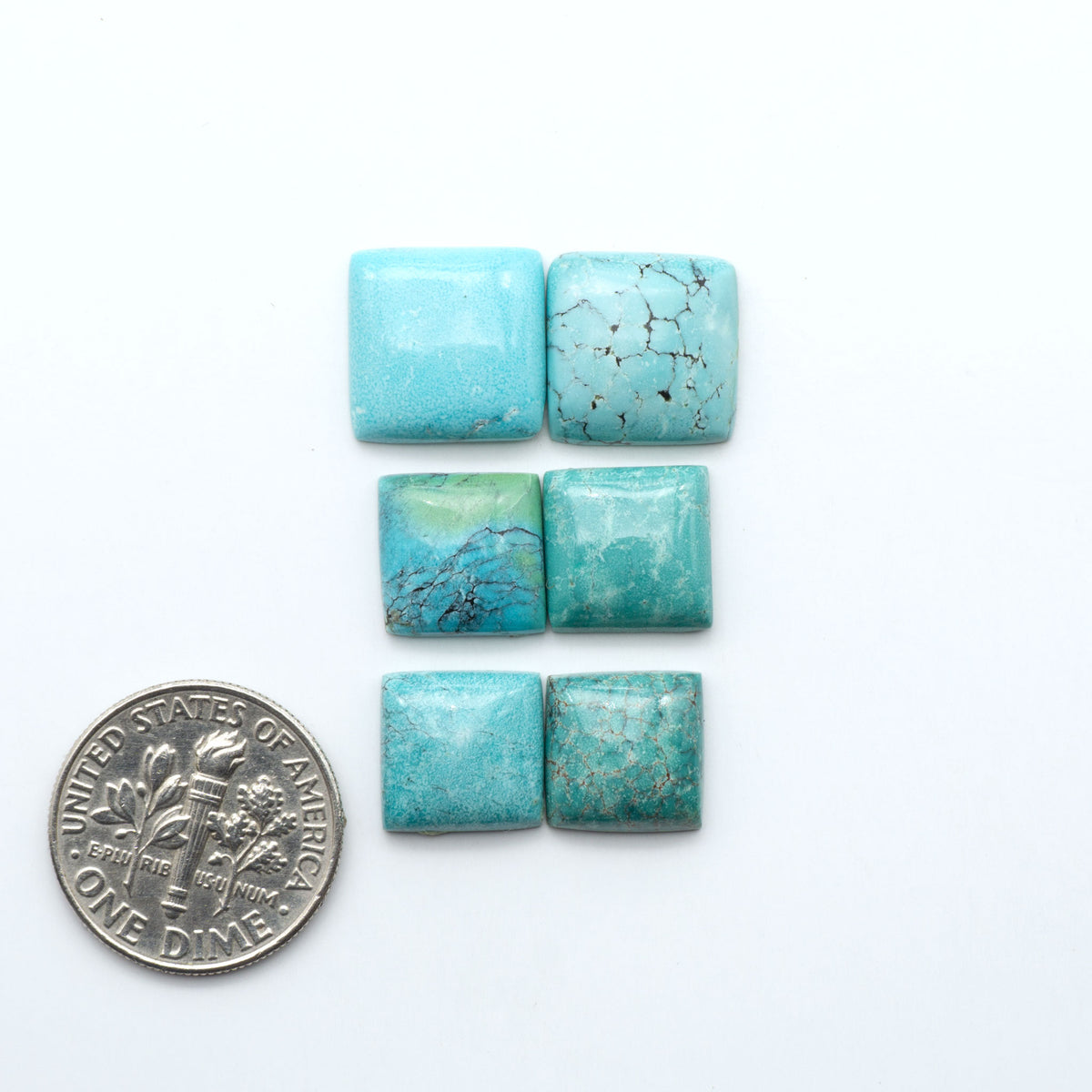 Hubei Cloud Mountain Turquoise cabochons, blue and green color with black matrix, polished stones on a white background, with a US dime for scale